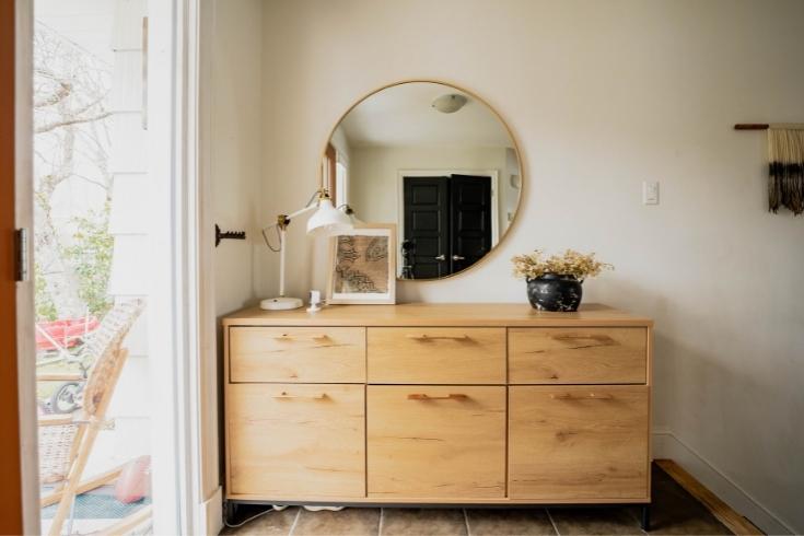 Round mirror in a boho-chic family home with over six-drawer pine dresser