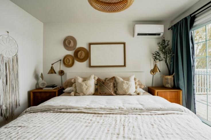 boho-chic family home bedroom with a white bed with mirror and three hats on wall
