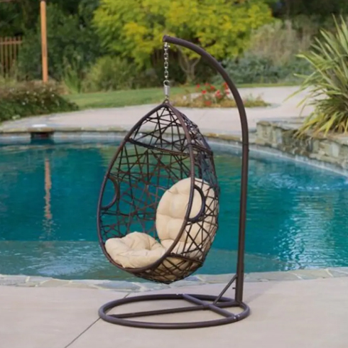 A hanging wicker egg chair by the pool.