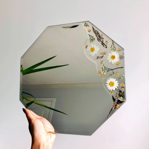 A unique-shaped mirror painted with daisies.