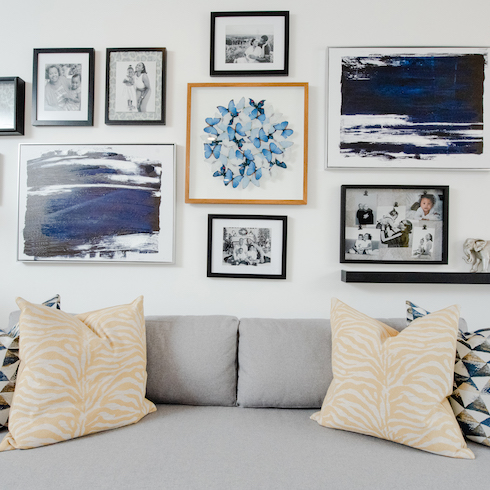 A living room with a photo collage and yellow pillows on a grey couch