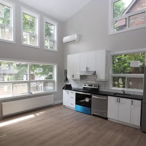 A loft apartment kitchen with high ceilings, floor to ceiling windows and hardwood floors