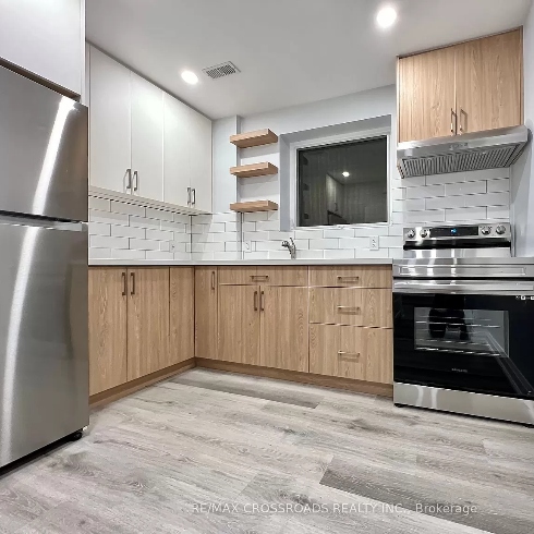 A kitchen with stainless steel appliances, light toned laminate flooring and light wood cabinetry