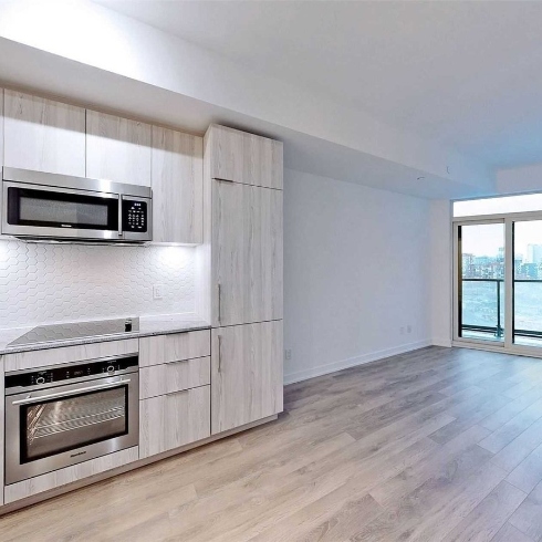 An open concept condo kitchen, dining room and living area with sliding glass doors to a balcony