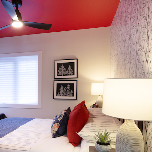 Cottage bedroom with a bright red ceiling and a feature wall with light wallpaper