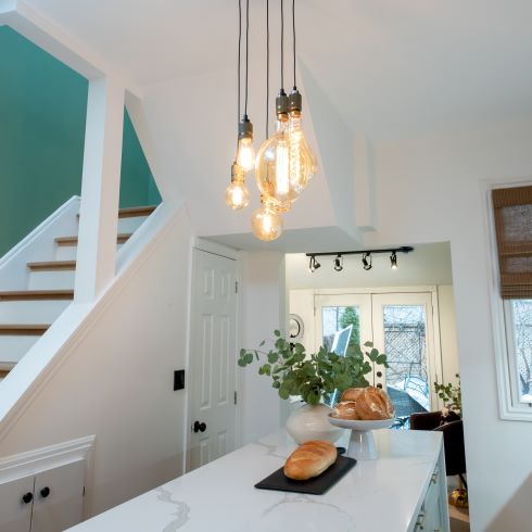 Open white kitchen with hanging Edison bulbs