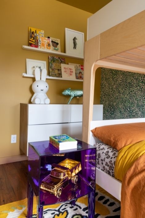 purple table, orange blanket bunk bed, mustard wall with shelves
