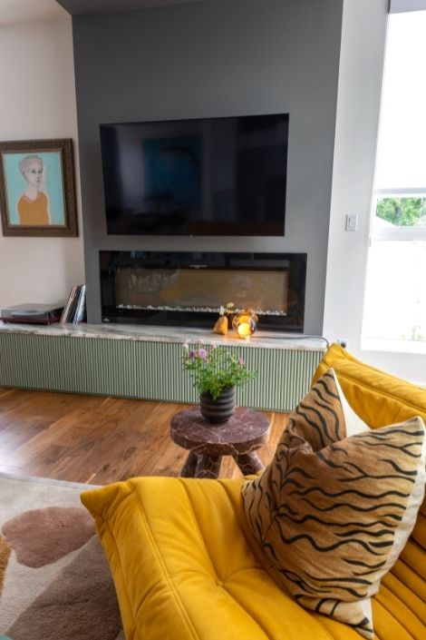 bright yellow floor chairs and cushion, green painted fireplace and TV behind