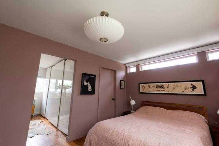 mauve bedroom with white ceiling light and high long window near ceiling