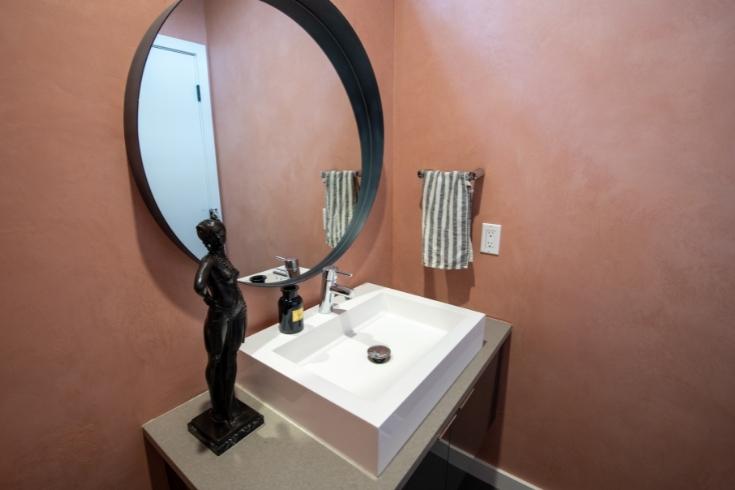 mauve powder room, round mirror, black statue, white sink