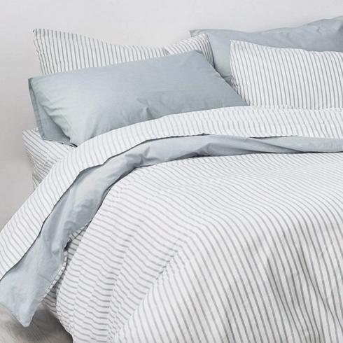 Blue and white sheets in a white bed.