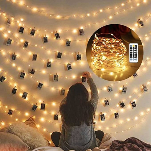 Fairy lights in a dorm room with printed photos hung on the wall.