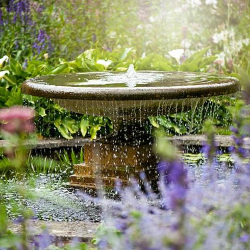 Beautiful garden fountain surrounded by colourful flowers as part of memorial garden ideas