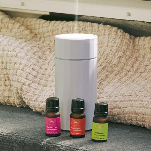A white diffuser with three bottles of essential oils.