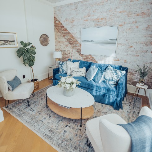 Living room with blue couch and exposed brick walls
