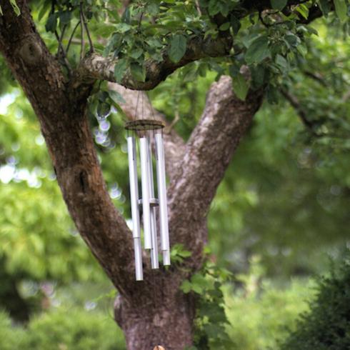 Metal and wood wind chimes hangs from a large apple tree can be part of a memorial garden