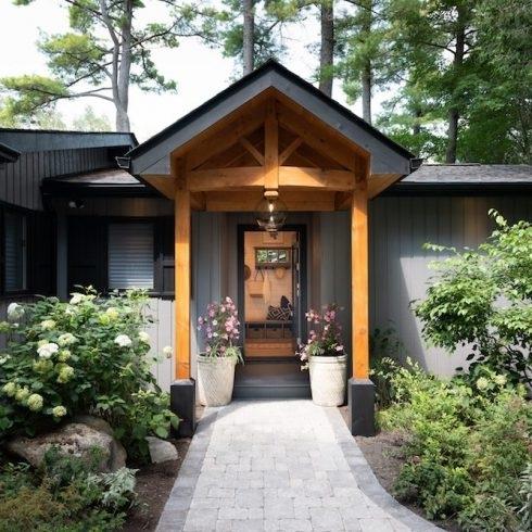 The front entrance to a rustic Canadian cottage lined with plants