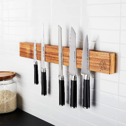 A wooden wall-mounted magnetic knife block with various kitchen knives