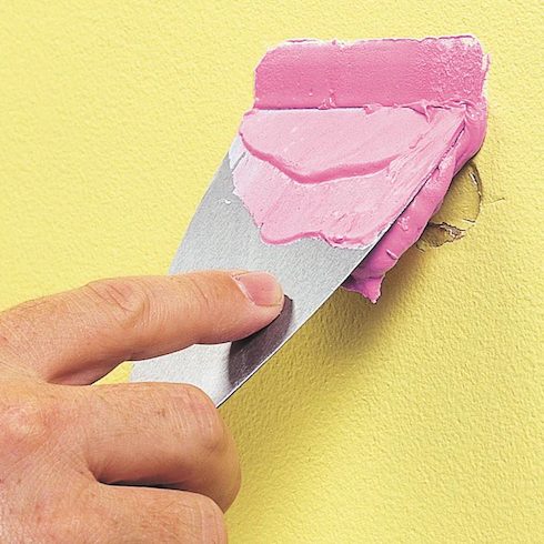Dap Drydex being applied to a yellow wall as part of painting essential tools