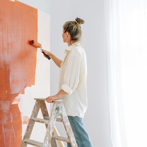 Close up of a person painting a wall as part of painting kit of essential tools