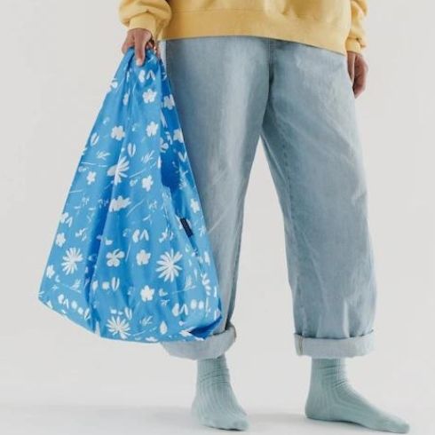 Person holding a blue floral reusable shopping bag