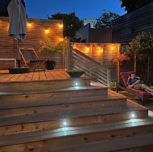Deck lit up at night with string lights and deck lighting