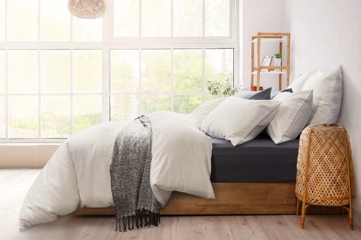 Bed with sustainable bedding, fluffy pillows in a white room
