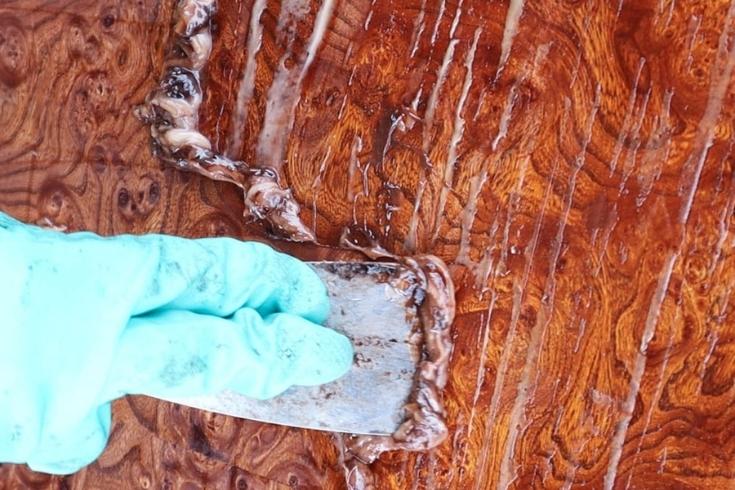 Wearing blue glove and staining a wooden table