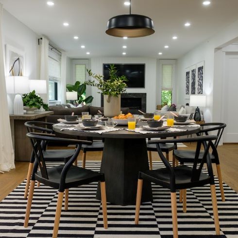 A casual black and white themed dining room with a bold pattern area rug