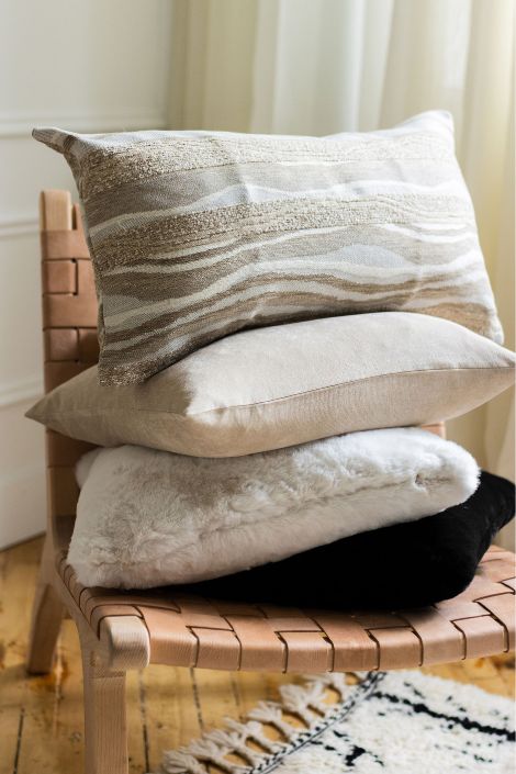 Pillows stacked on top of one another on a brown chair 