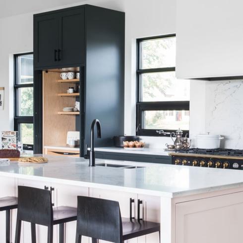 A kitchen with white counters, black cabinets and black counter tops.