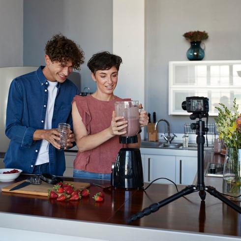 Couple making smoothie and vlogging in their kitchen.