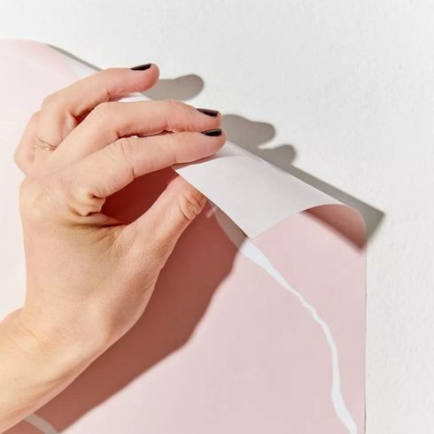 Close up of person hanging pink removeable wallpaper
