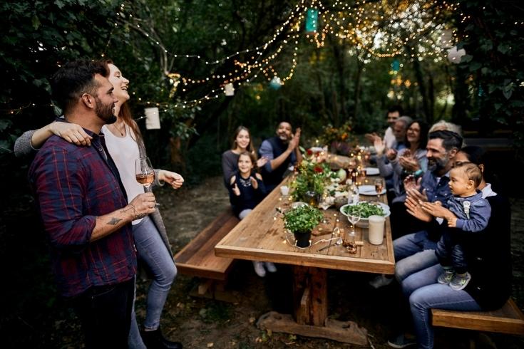 A couple smiling and making a toast in an outdoor dinner party.