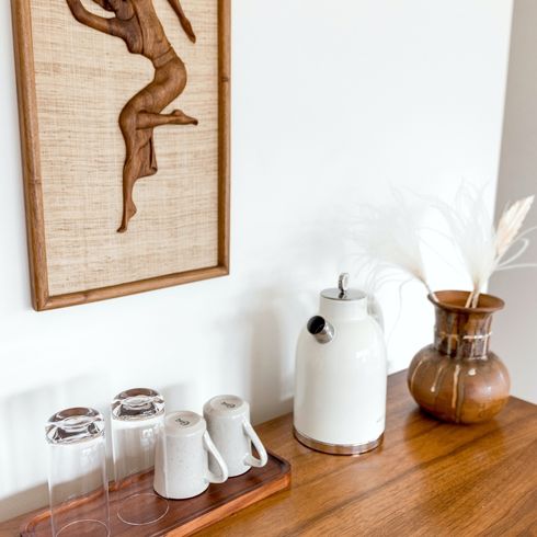 empty cups and a kettle on top of a sideboard