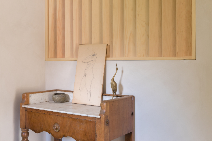 A half-wall angled wooden slat divider with a small accent table against it.