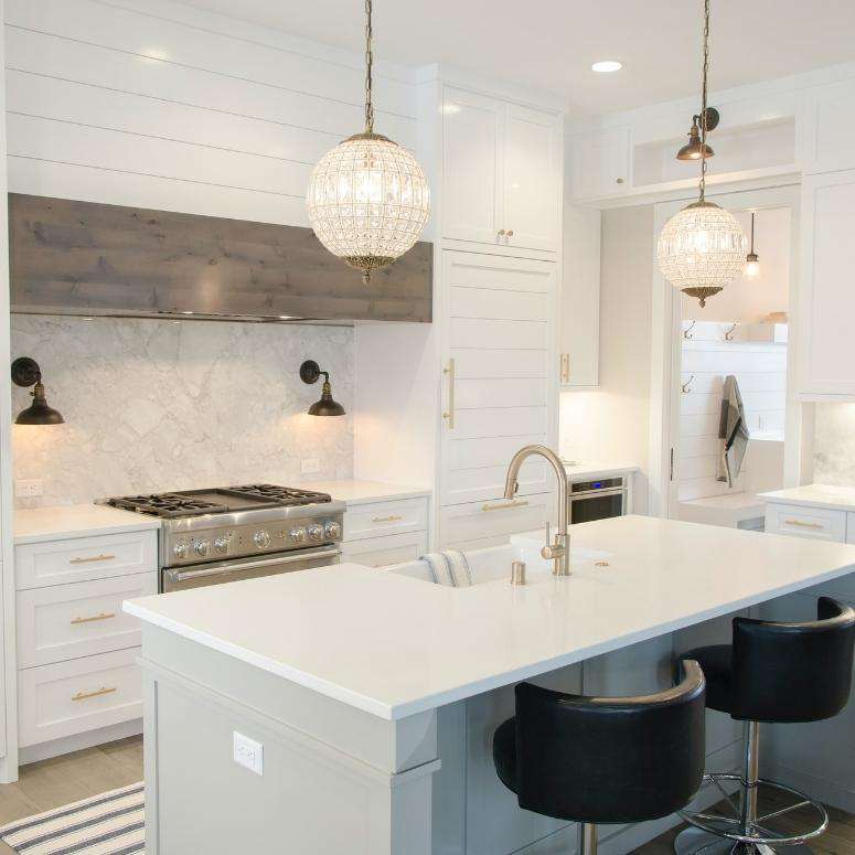 A luxury white kitchen with white countertops and white cabinets.