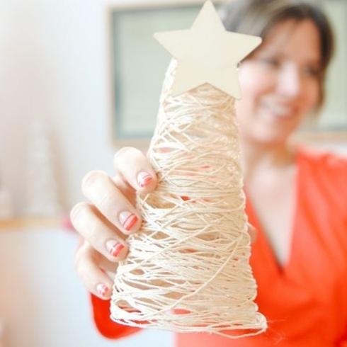 A person holding a Christmas tree craft made out of string