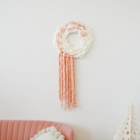A modern holiday wreath made with pink and white yarn