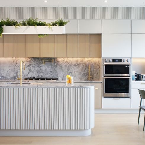 Curved, fluted island in pale kitchen with hanging planter