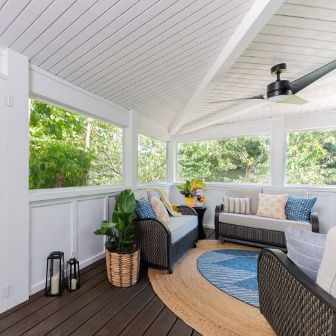 Renovated white screened-in deck with a seating area and an overhead fan