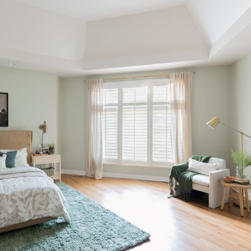 A light open bedroom with mint walls and lounge chair