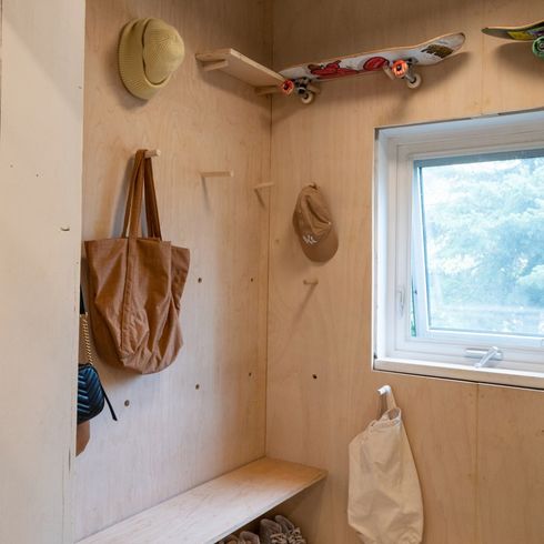 Plywood entrway in house with built-in bench and pegs