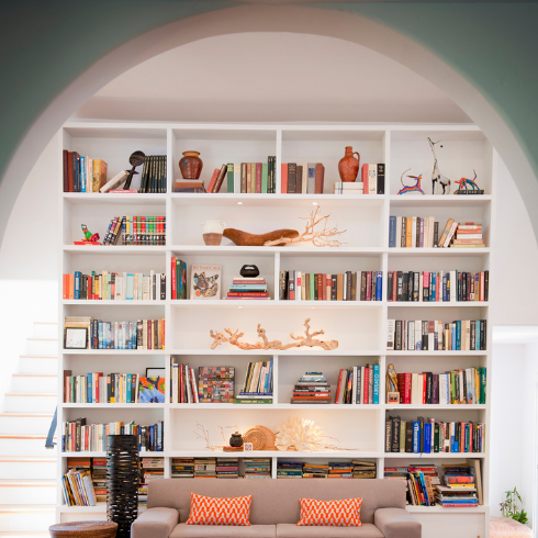 An arched doorway leading to a built-in bookcase