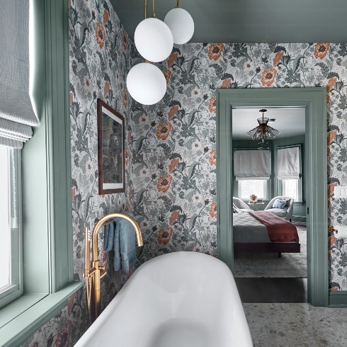 Primary bathroom with standing tub and floral wallpaper