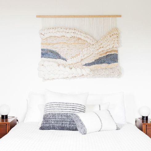 White and blue macrame wall art hanging above a matching bed in the guest bedroom