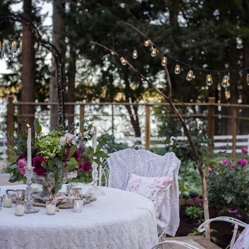 The table in the rose garden, with white linens and a pink rose-patterned pillow