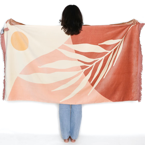 View of a back of woman holding up The Dunes Beach Towel from Tofino Towel Co. as featured in HGTV’s Canadian Gift Ideas from Homegrown Small Businesses for Under $100