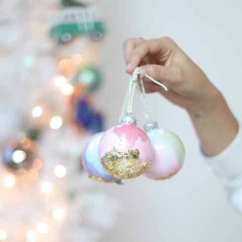 Person holding pastel Christmas ornaments.