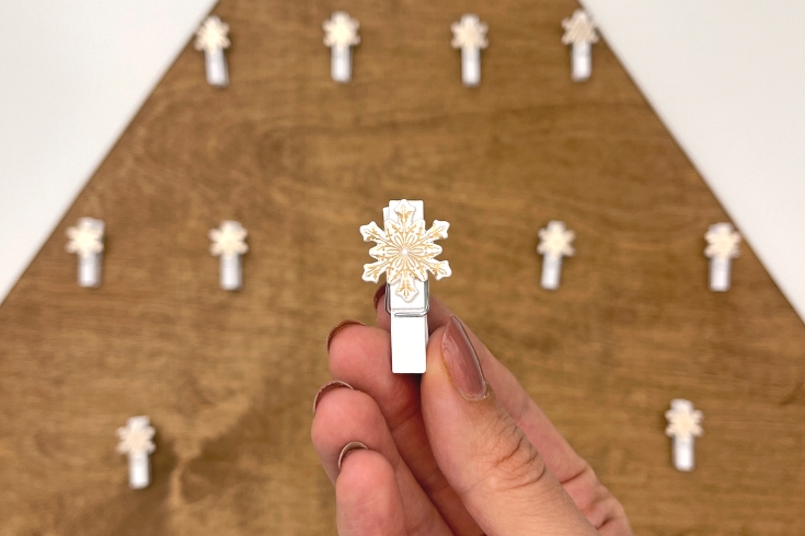 Woman holding a wooden peg in the shape of a snowflake